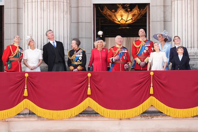 The Royal Family on the Buckingham Palace balcony watching the flypast at Trooping the Colour, including King Charles, Queen Camilla, Prince William, Kate Middleton, Princess Anne, and other members of the extended royal family.