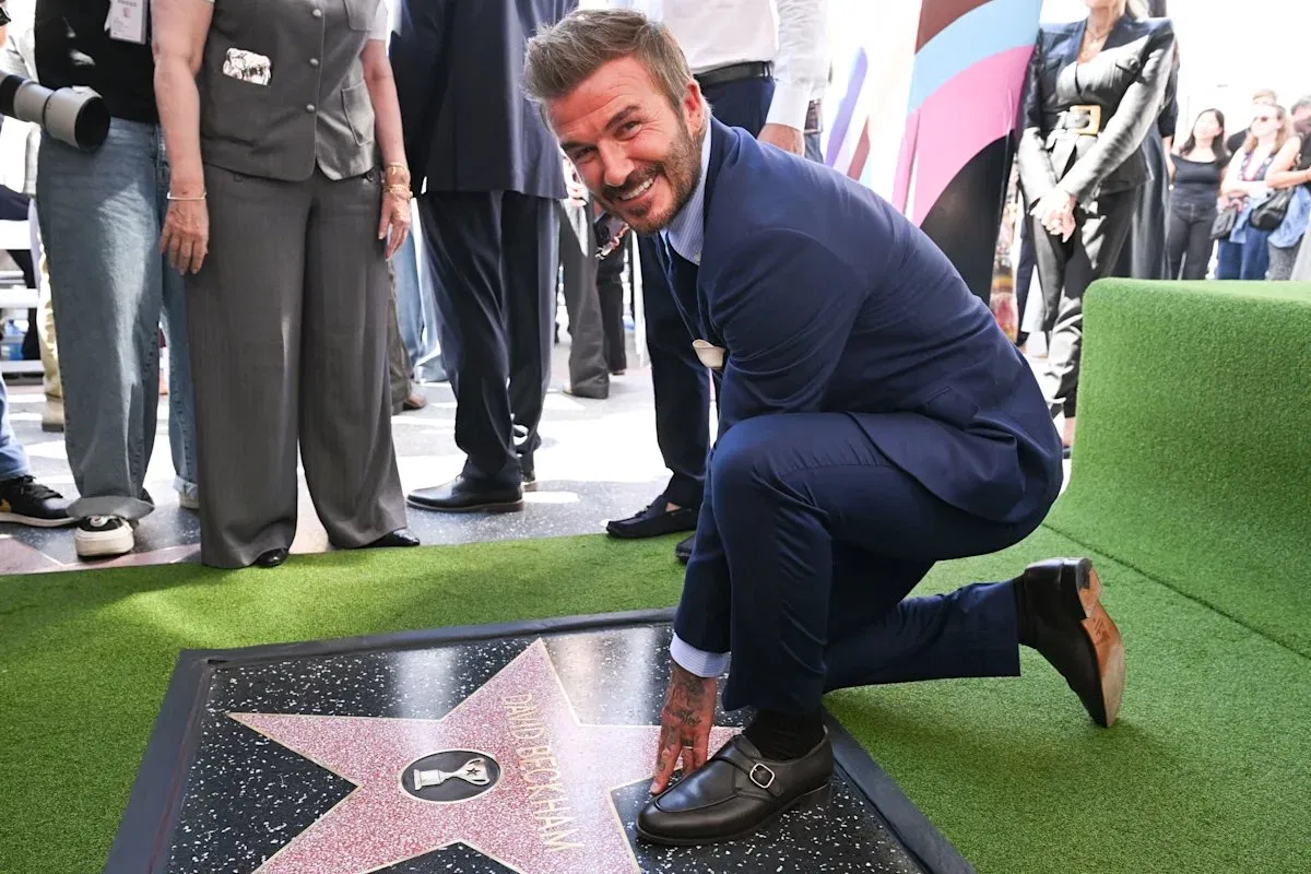 David Beckham crouching beside his star on the Hollywood Walk of Fame.