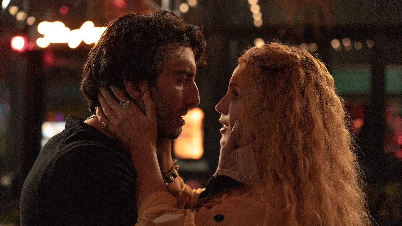 Blake Lively and Justin Baldoni face each other intimately on a nighttime city street with blurred lights in the background in a still from It Ends With Us