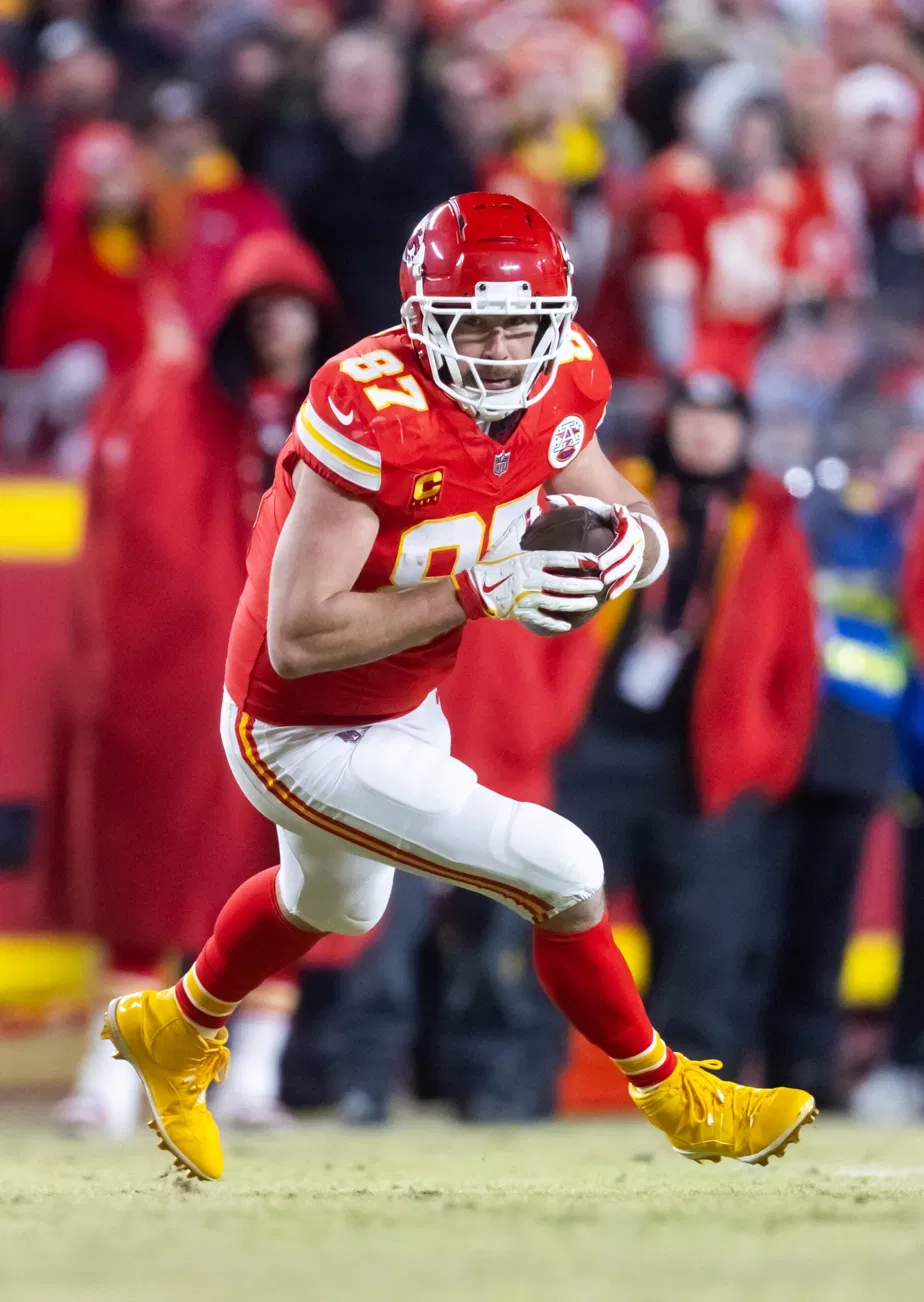 Travis Kelce running with the ball in his Kansas City Chiefs uniform during a game.