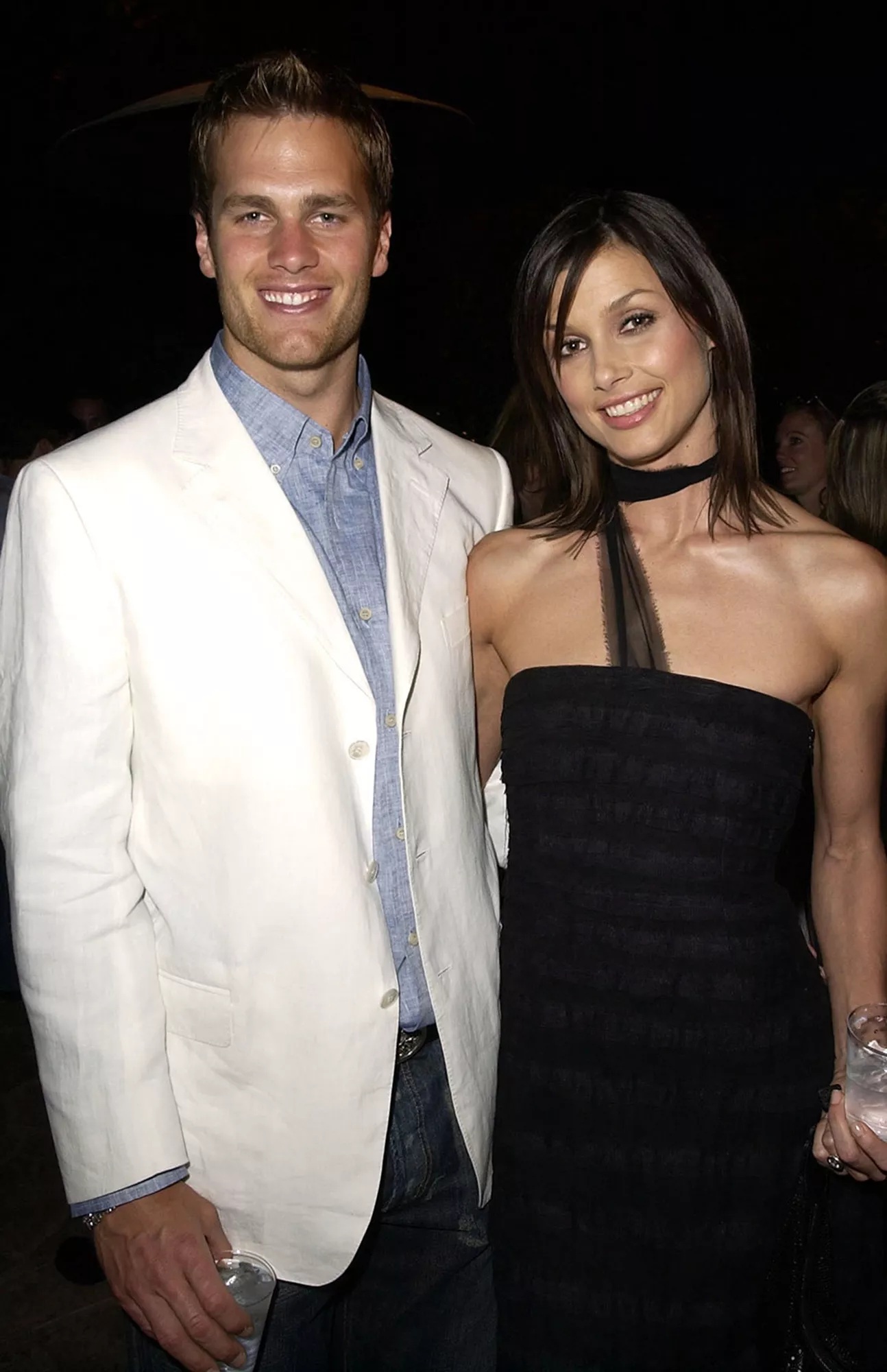 Tom Brady in a white blazer and Bridget Moynahan in a black strapless dress, smiling together at an event.