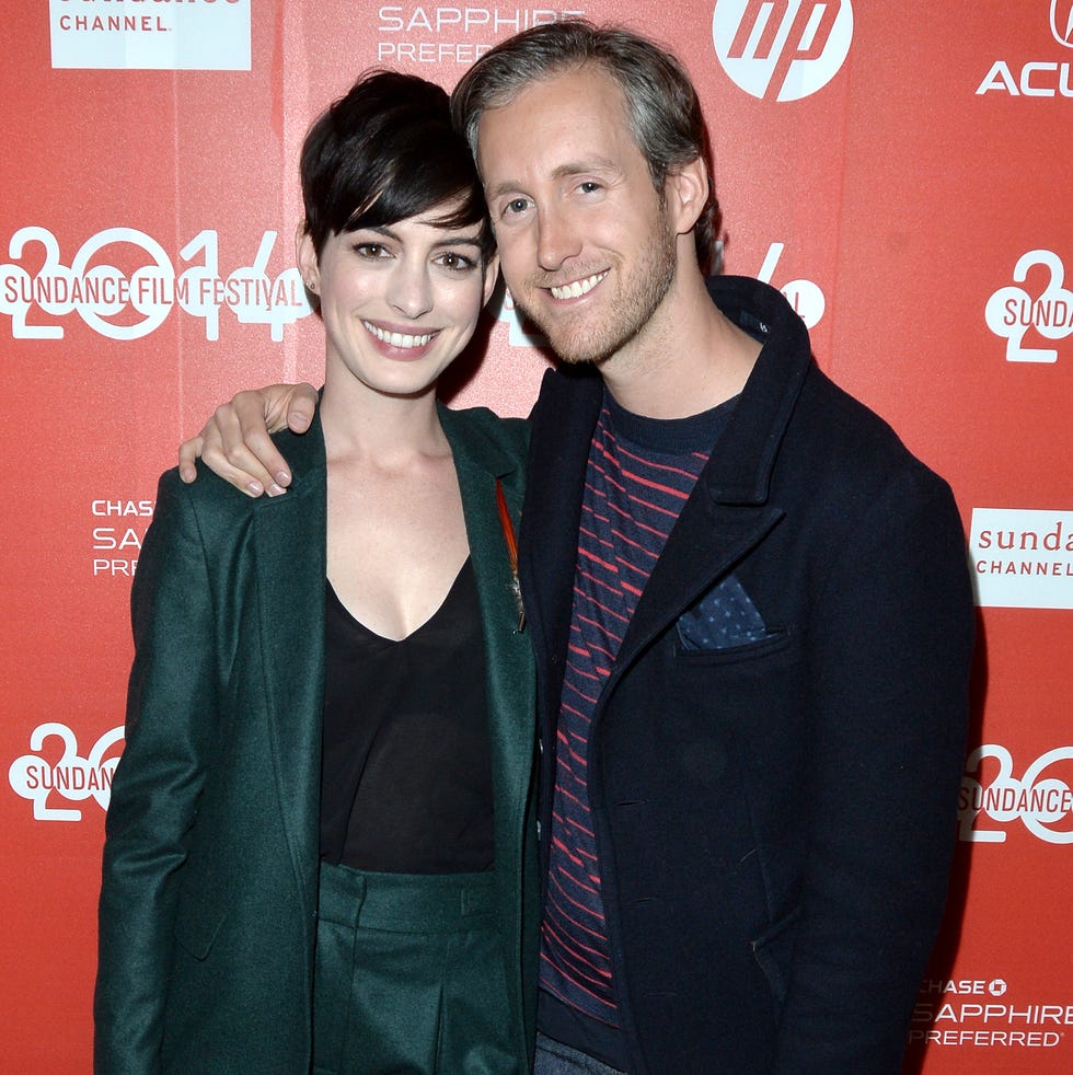 Anne Hathaway and Adam Shulman posing together at the 2014 Sundance Film Festival against a red branded backdrop.