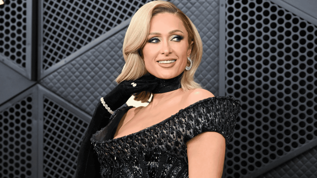 Paris Hilton with blonde hair wearing an off-shoulder black sequined dress and black choker against a geometric metallic background.