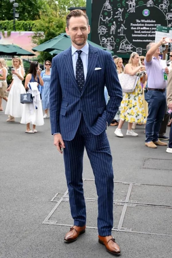 Tom Hiddleston brought his usual sartorial polish in a navy pinstripe suit and light blue shirt.