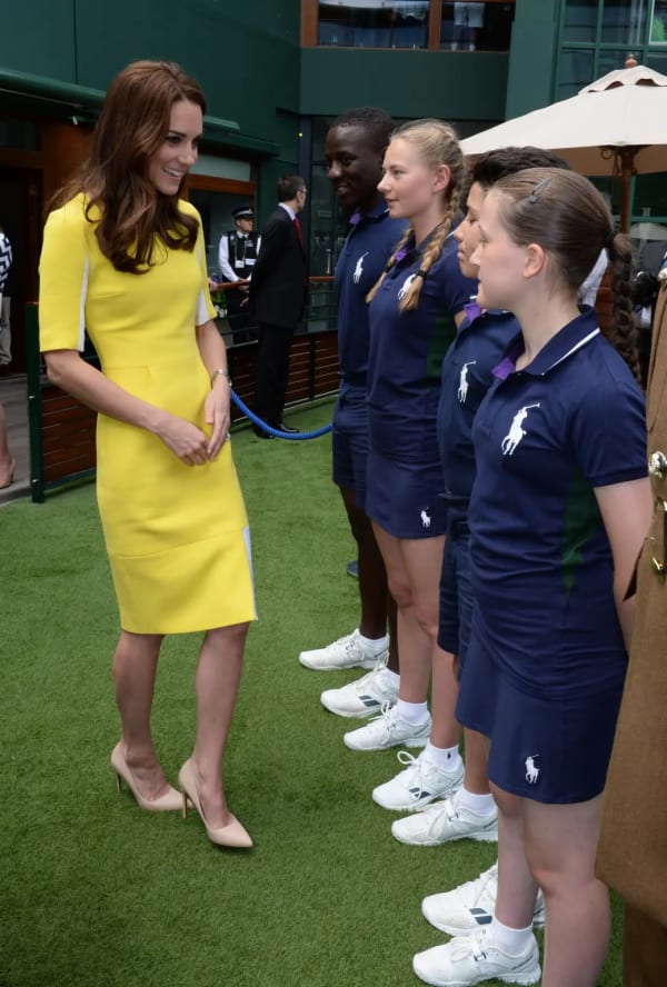 Chatting with ball boys and girls at the 2016 Championships, the Duchess wore a canary-yellow Roksanda dress with white contrast panels — a rewear of the Serbian designer's bespoke creation she had first sported in Sydney in 2014. | Photo: Getty Images