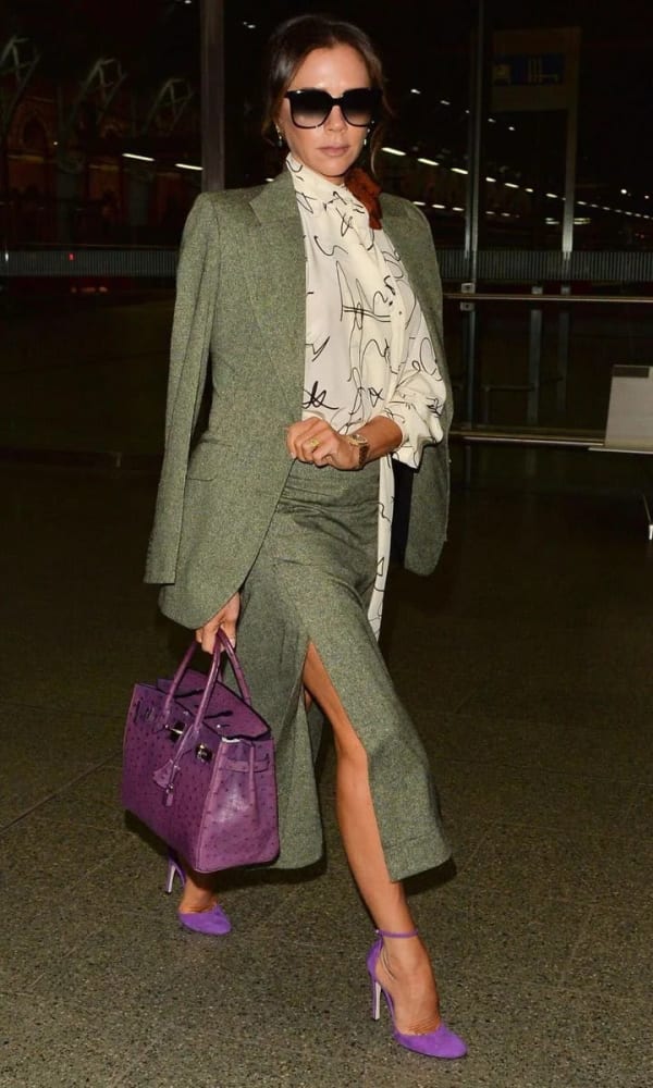 Victoria Beckham strides through St Pancras International in December 2019, boarding the Eurostar to Paris in a green tweed co-ord teamed with a purple ostrich Hermès Birkin and matching violet suede heels.