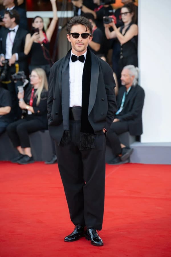 Giorgio Armani Global Fragrance Ambassador Jonathan Bailey commands the red carpet at the 83rd Venice Film Festival in a show-stopping Giorgio Armani tuxedo complete with barrel-leg trousers, velvet bow tie, and fringed waistband.