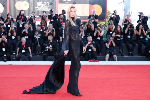 Stella Maxwell was an arresting vision in a sheer black lace Intimissimi column gown with long sleeves and a sweeping satin cape train, the delicate lace-over-black underlining creating a beautifully layered effect. - Getty Images.