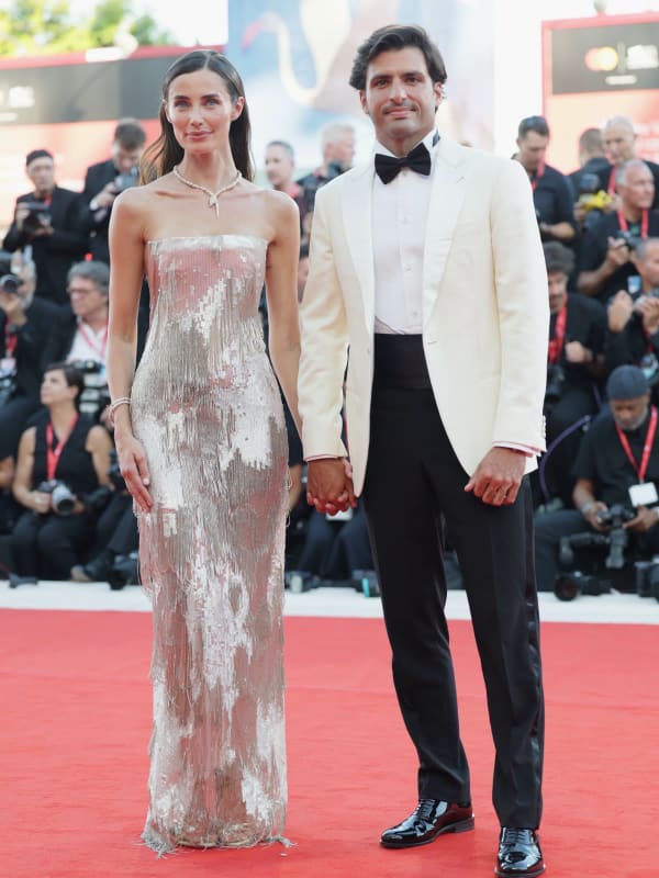 Formula 1 champion Carlos Sainz wore a Giorgio Armani Made to Measure ivory dinner jacket, while his partner Rebecca Donaldson shimmered in a strapless silver fringed Giorgio Armani gown, the couple making a dazzling duo at the festival's opening ceremony. - Getty Images.