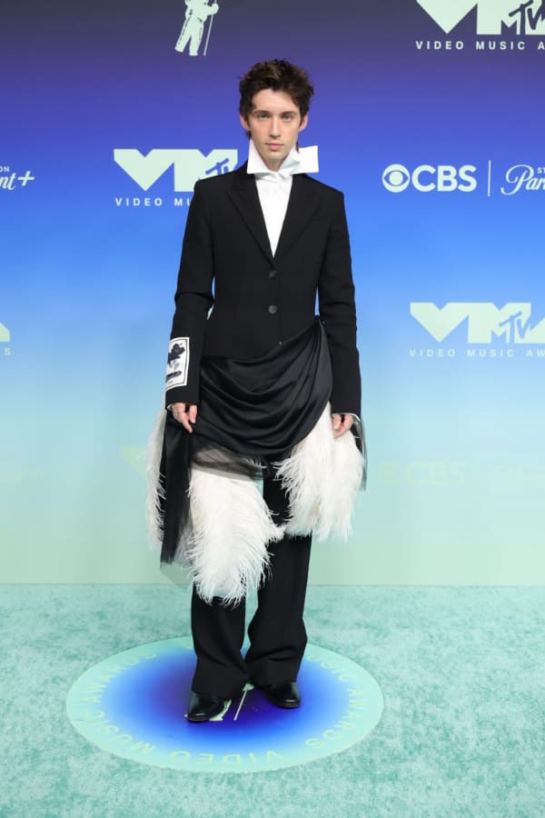 Troye Sivan turned heads at the 2026 MTV VMAs in a fresh-off-the-runway Erdem Spring/Summer 2027 look, subverting the classic tuxedo with a dramatic burst of white ostrich plumes and a trailing sweep of satin and tulle.