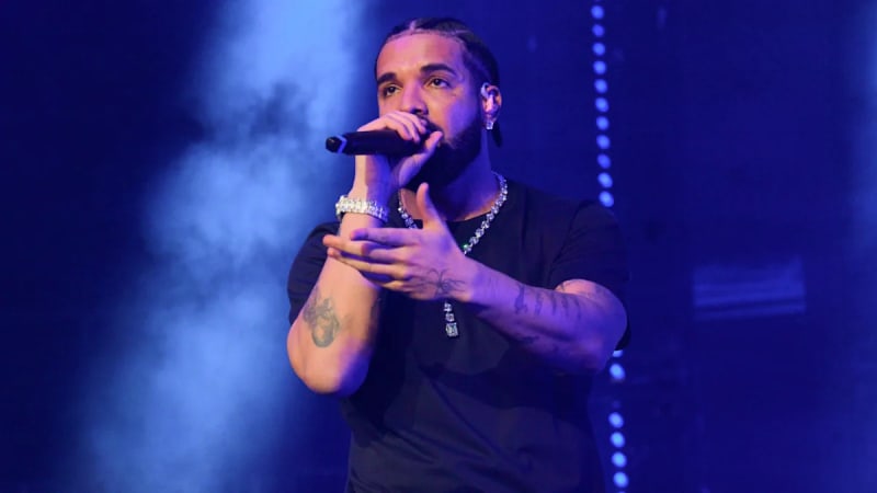 Drake performing on stage under bright spotlights during a live concert