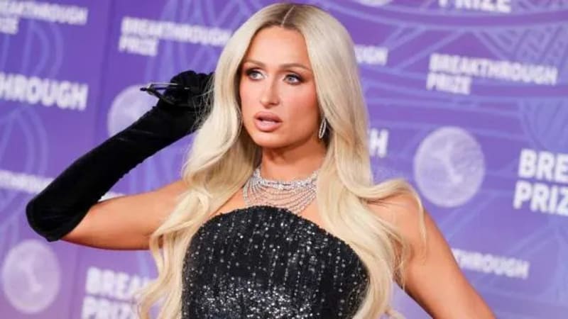 Paris Hilton with long platinum blonde hair wearing a black sequined dress and long black gloves at a purple-themed event.