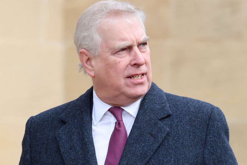 Andrew Mountbatten-Windsor in a navy tweed overcoat and red tie at a public engagement.