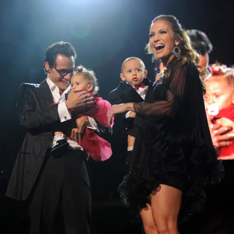 Marc Anthony and Jennifer Lopez holding their twin babies Emme and Max on stage.