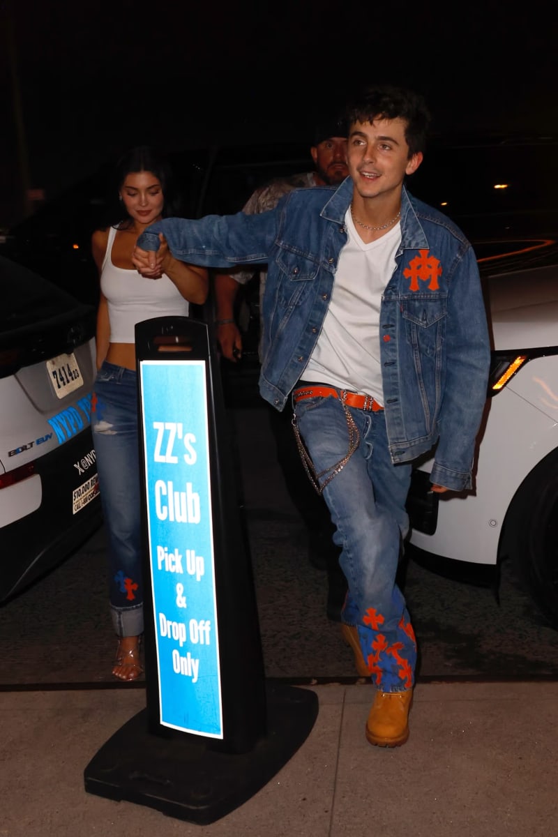 Timothée Chalamet and Kylie Jenner arriving hand in hand at ZZ's Club in Knicks-colored Chrome Hearts denim outfits.