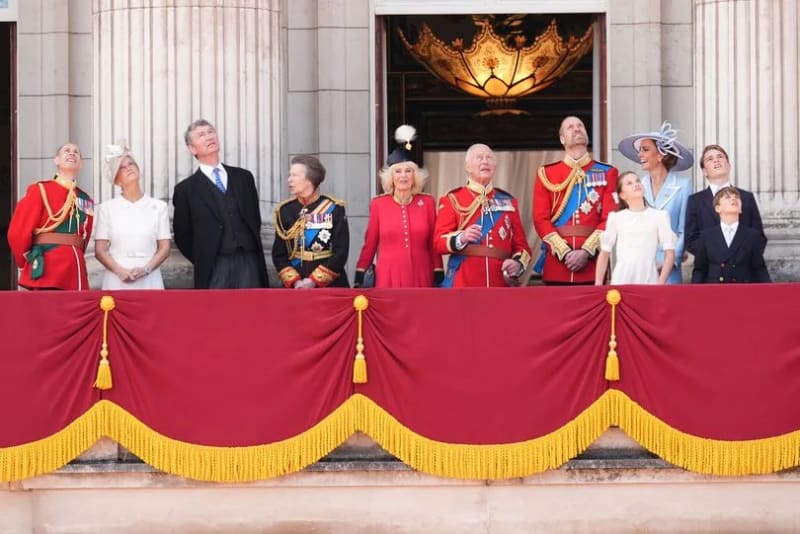 The Royal Family on the Buckingham Palace balcony watching the flypast at Trooping the Colour, including King Charles, Queen Camilla, Prince William, Kate Middleton, Princess Anne, and other members of the extended royal family.