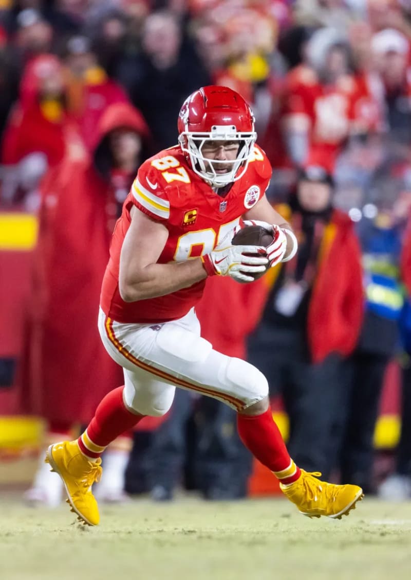 Travis Kelce running with the ball in his Kansas City Chiefs uniform during a game.