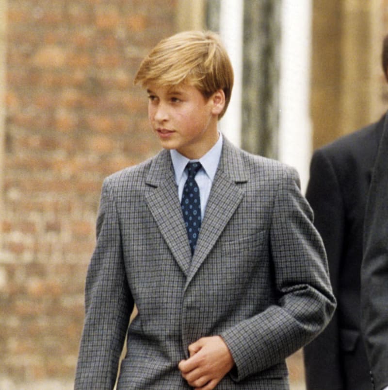 A young Prince William in a grey checked suit and blue patterned tie on his first day at Eton College.