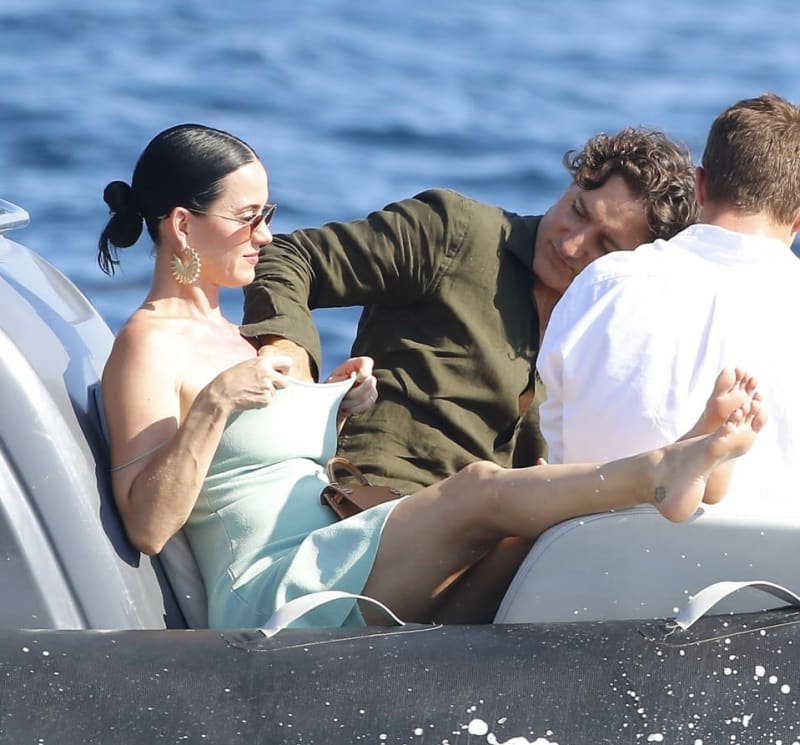 Three people sit together on a boat with blue ocean water in the background.