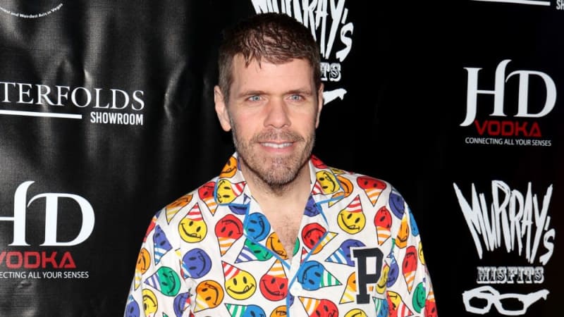 Man with beard wearing colorful patterned shirt at event with HD Vodka and Murray's branding visible in background.