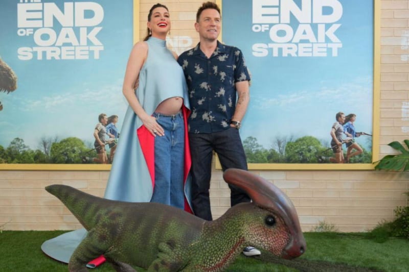 Two people pose with a large fish sculpture at an "End of Oak Street" movie premiere event.