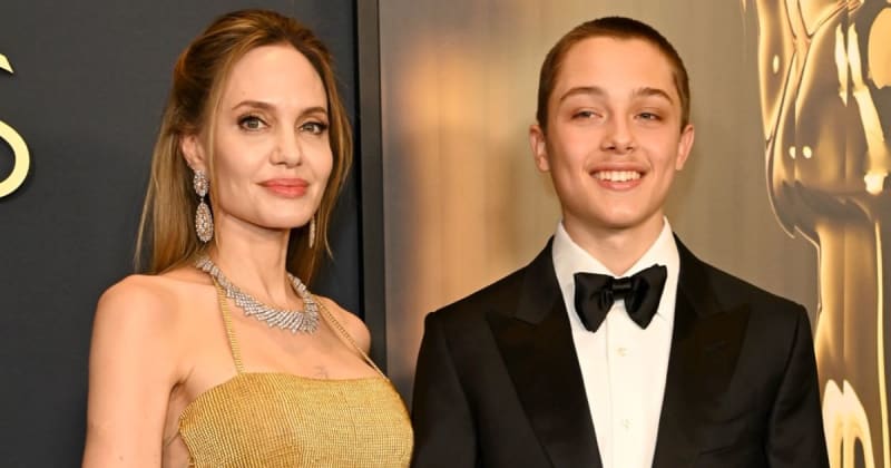Two people in formal attire at an elegant event; woman in gold dress with diamond jewelry and man in black tuxedo with bow tie.