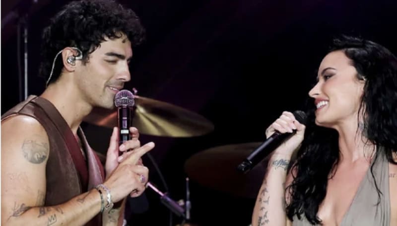 Two performers singing together on stage with microphones during a live concert performance.