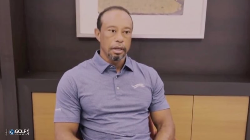 A man in a purple polo shirt being interviewed on the Golfy Channel, seated against a brown and dark backdrop.