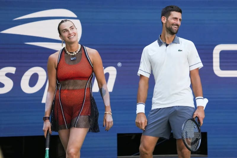 Woman in red mesh tennis dress and man in white polo holding rackets, US Open backdrop.