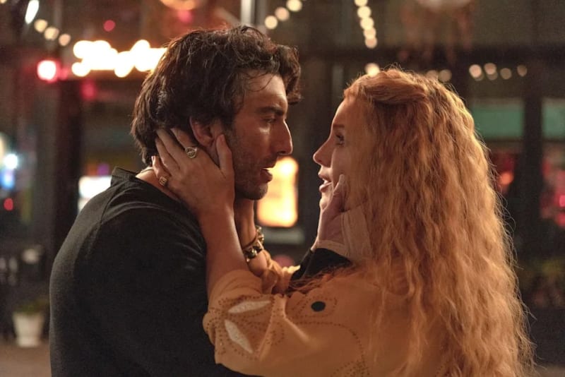 Two people facing each other on a nighttime city street with blurred lights in the background.