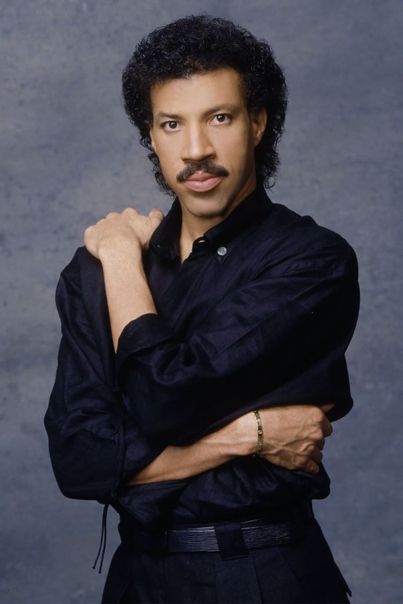 Man in black shirt, arms crossed, studio portrait