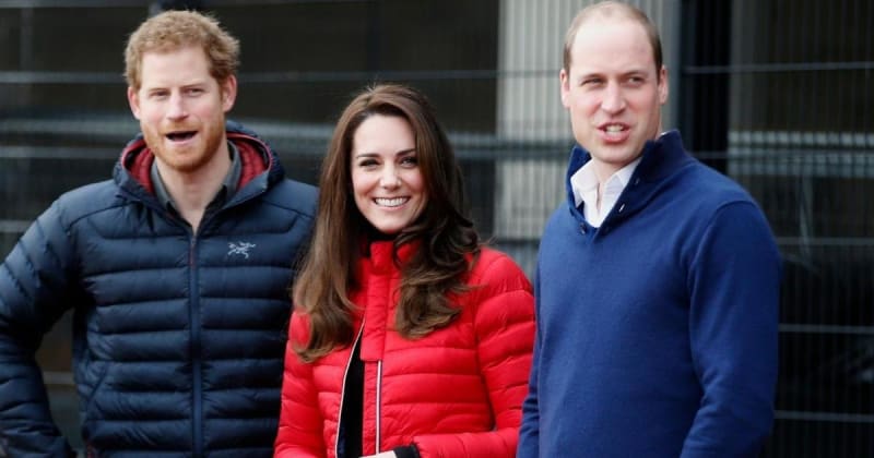 Three people smiling outdoors wearing winter jackets - a man in navy left, a woman in red center, and a man in navy right.