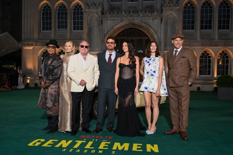 Cast members pose on the green carpet at the Netflix "Gentlemen: Season 2" premiere in front of an ornate Gothic building.