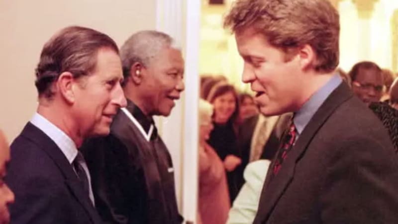 Three men in formal attire engaged in conversation at what appears to be an indoor formal event or reception.