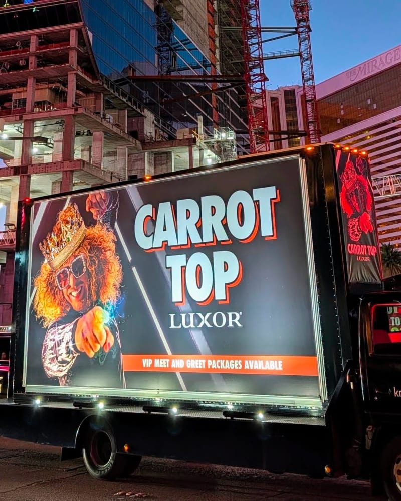 Mobile billboard truck advertising Carrot Top at Luxor, Las Vegas Strip at night.