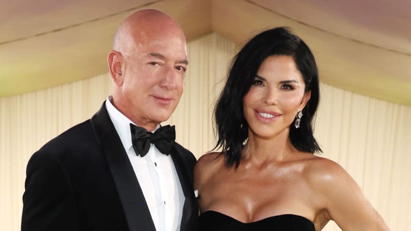 Two people in formal attire at an elegant event, with the man wearing a black tuxedo and bow tie and the woman in a black strapless dress.