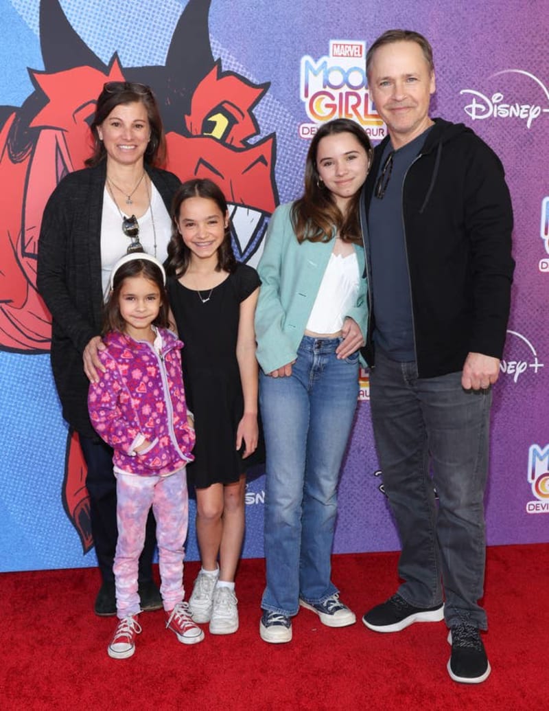 Family of five posing on red carpet at Marvel's "Moon Girl and Devil Dinosaur" premiere event.