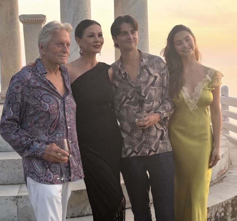 Two older adults and two young adults posing on a marble terrace at sunset.