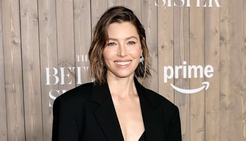 A woman with shoulder-length brown hair smiles at a red carpet event in front of a wooden backdrop and Prime Video branding.