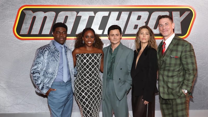 Five people posing in front of a Matchbox logo backdrop at a premiere event.
