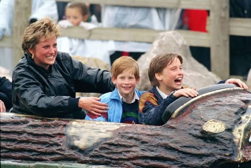 Woman and two boys laughing on a log flume ride at a theme park.