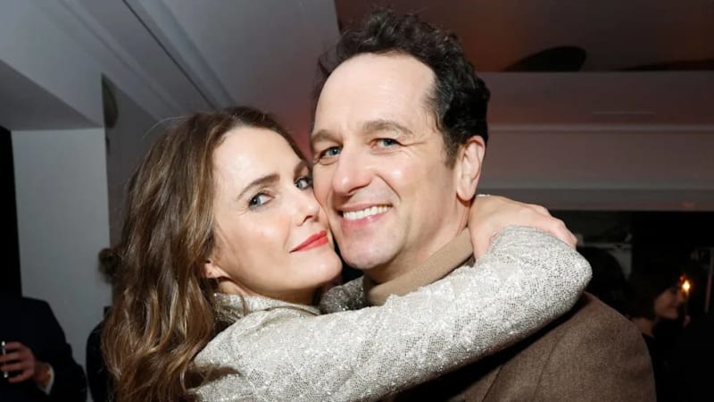 Two people embracing and smiling at an indoor event, with warm lighting in the background.