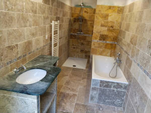 Salle de bain travertin avec baignoire, douche et sèche-serviettes