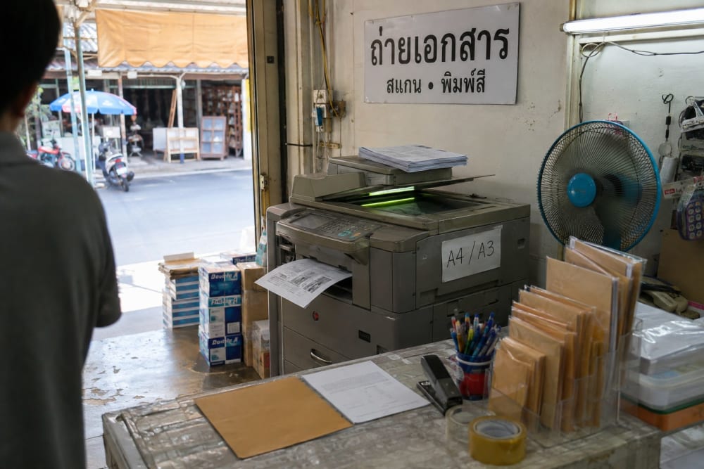 Échoppe de photocopie thaïlandaise, copieur en marche et enveloppes kraft sur le comptoir