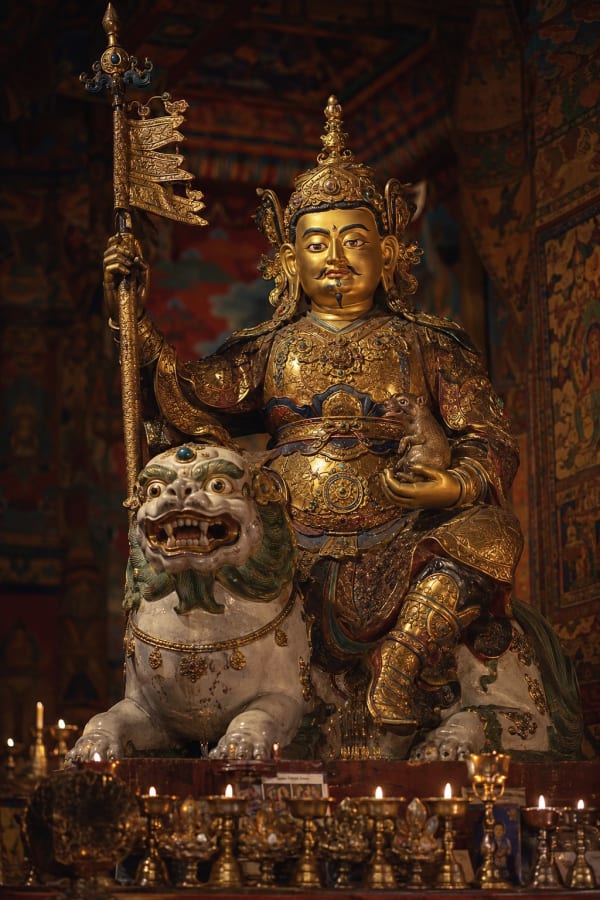 Vaiśravaṇa tibétain assis sur un lion des neiges, tenant une bannière