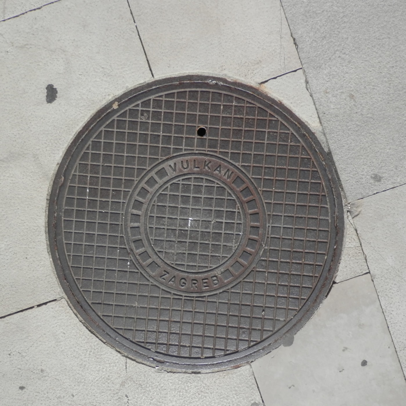 Mřížkový vzor tohoto exempláře, tvořený pravidelnými čtverci, dominuje jeho povrchu a je obklopen kruhovým nápisem. Zřet in Zagreb, Croatia — CoverSpot