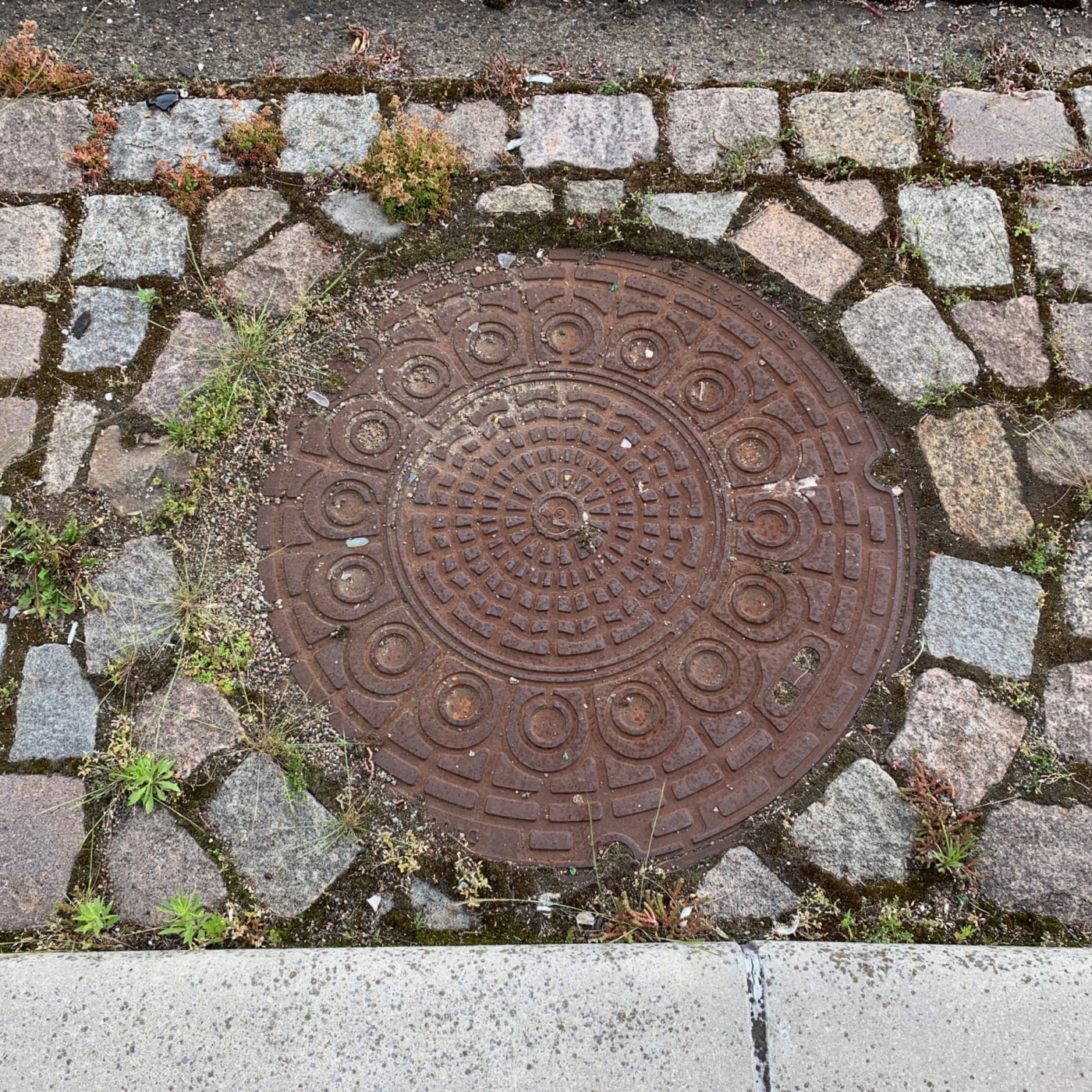 Složitý kruhový vzor, připomínající starověký labyrint, dominuje tomuto exempláři městské infrastruktury, obklopenému ne in Manhattan, New York, United States — CoverSpot