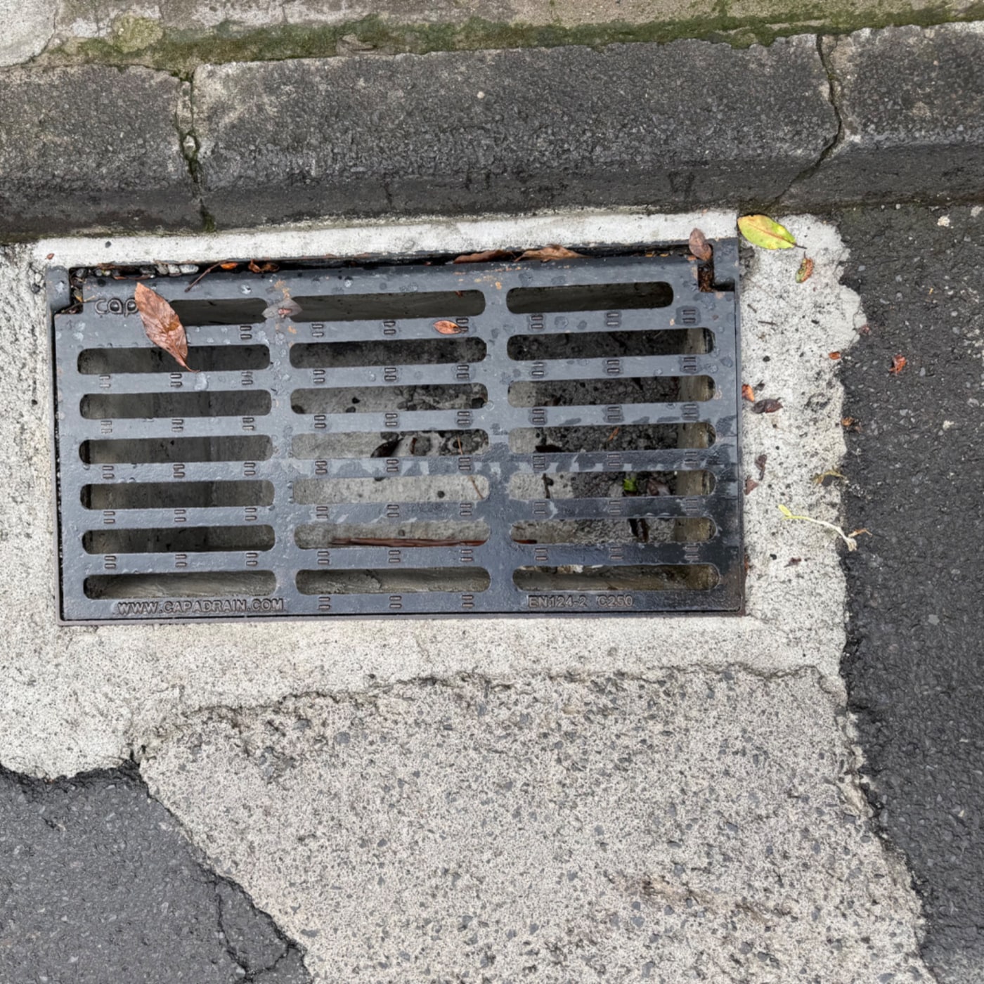 Na fotografii je vidět obdélníková kovová mříž, která slouží pravděpodobně k odvodnění. Je zasazena do betonového rámu m in Santa Luzia, Madeira, Portugal — CoverSpot