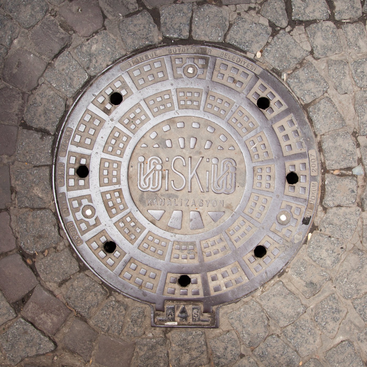 Do dlažby z hrubých kamenných kostek je zasazen kruhový kovový disk, jehož povrch zdobí složitý geometrický vzor s centr in Istanbul, Turkey — CoverSpot
