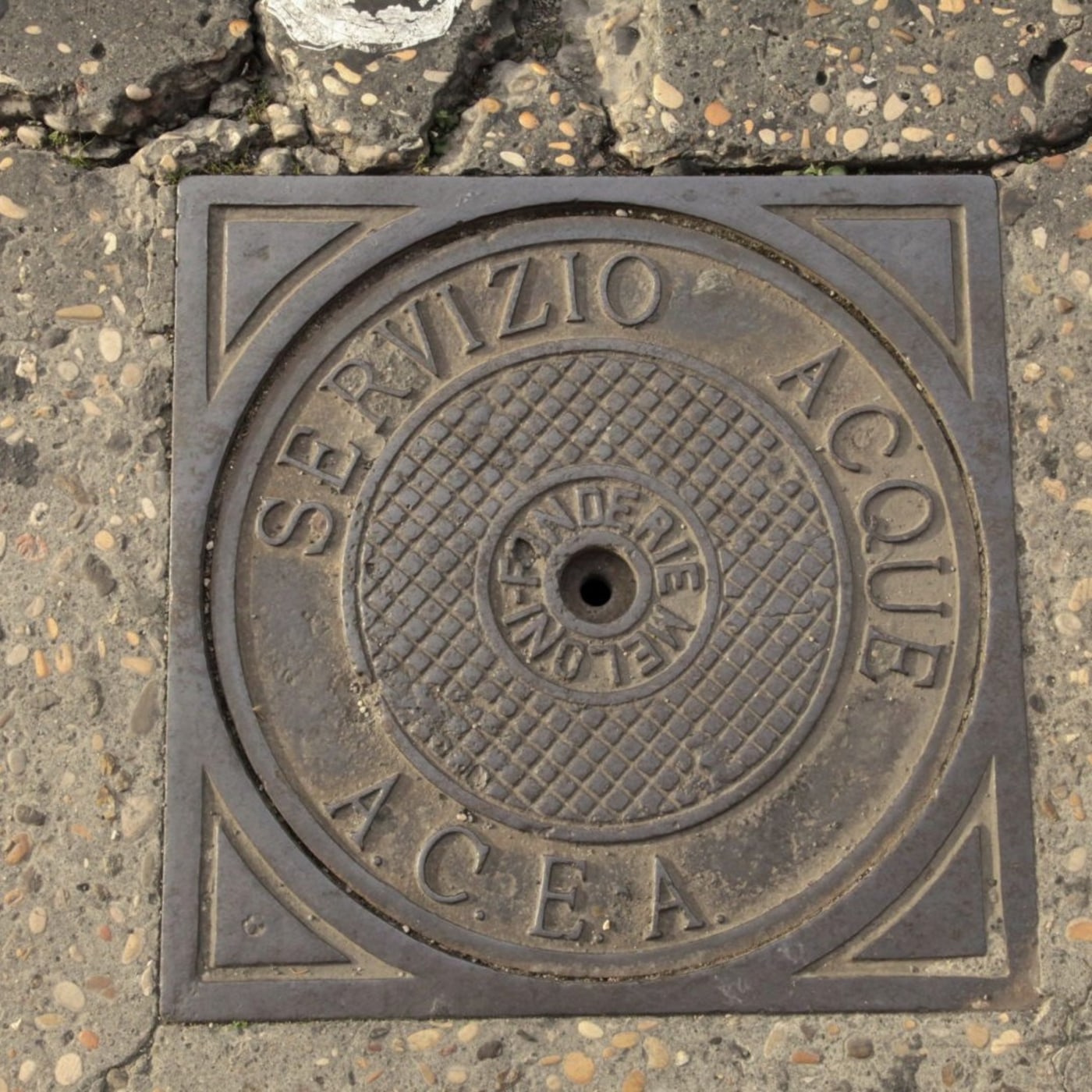 Kruhový reliéf s nápisem 'SERVIZIO ACQUE' jasně identifikuje tento exemplář jako součást vodovodní infrastruktury. Centr in Rome, Italy — CoverSpot